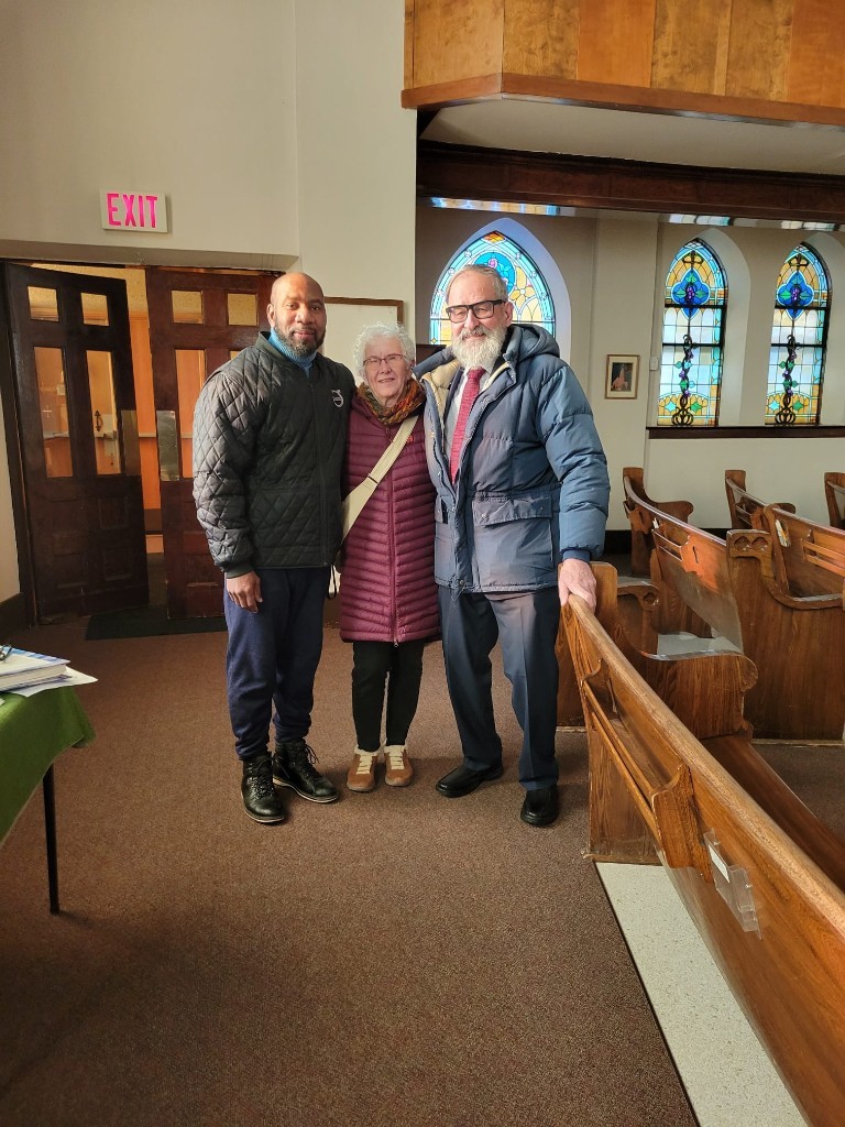 Johnson Philip with two parishioners inside a church