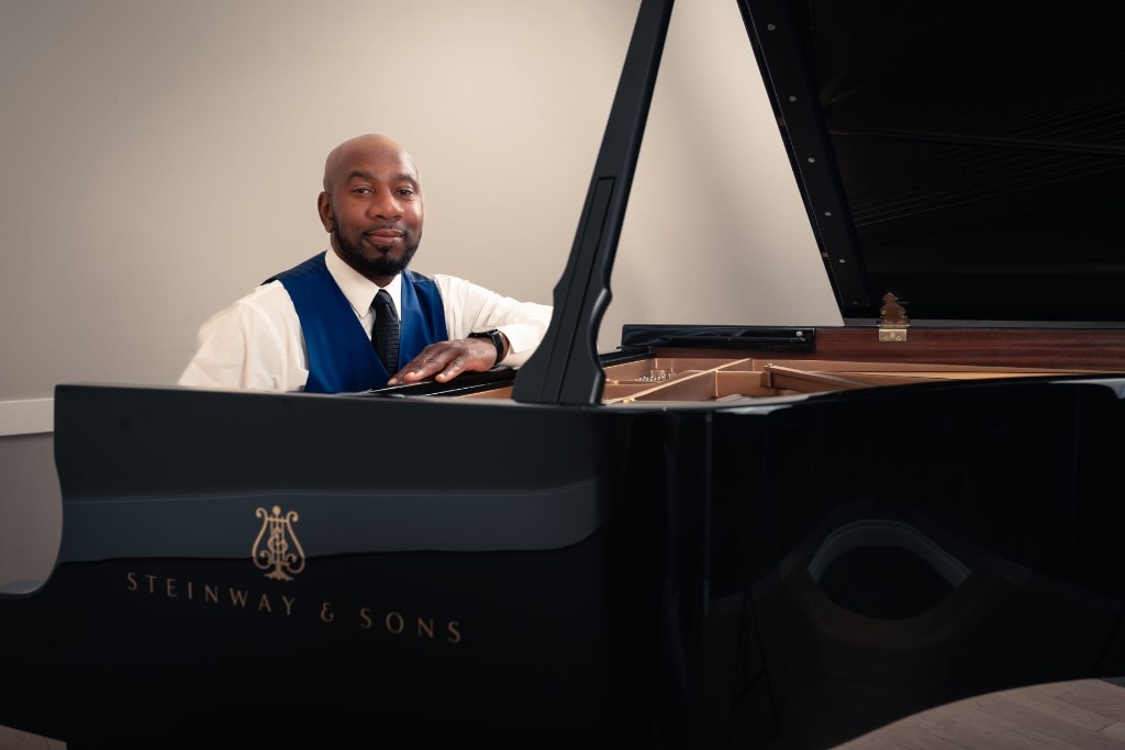 Johnson Philip smiling beside a Steinway grand piano